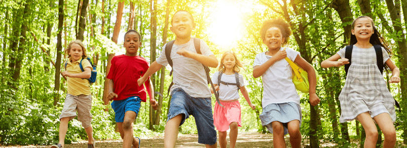 Six kids running on a trail through a forest during the summer. BGC Okanagan Summer Full Day Child Care registration is now open.