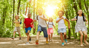 Six kids running on a trail through a forest during the summer. BGC Okanagan Summer Full Day Child Care registration is now open.